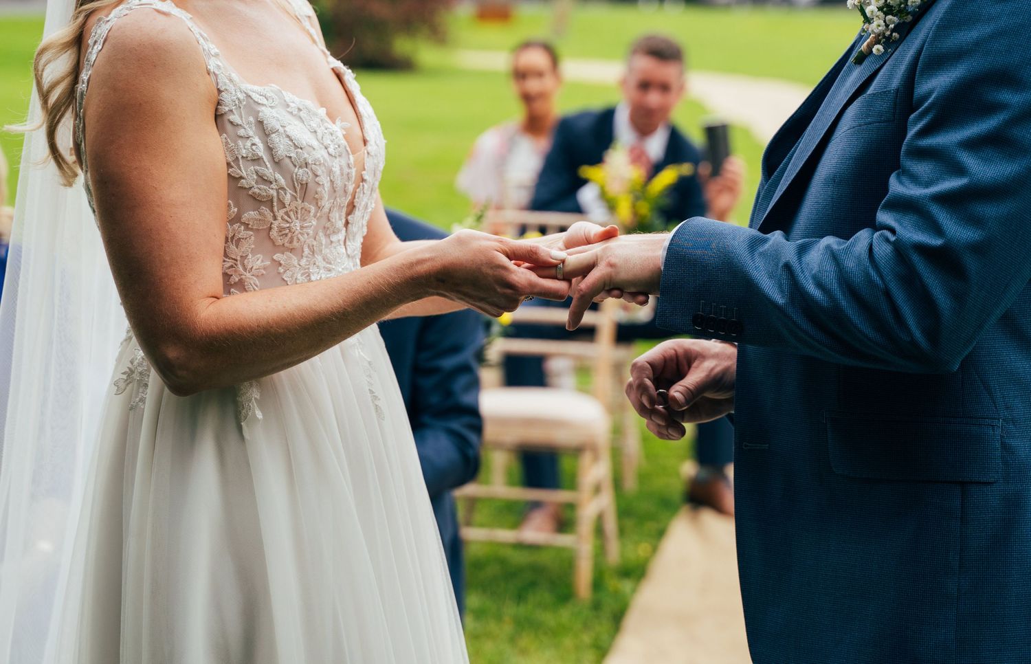 Bride and groom exchanging rings during an outdoor wedding ceremony with guests seated in background at Bellinter house.