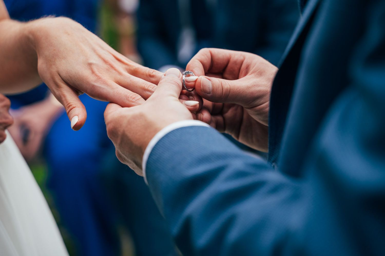 Groom placing a wedding ring on bride's finger during ceremony, close-up of hands in elegant wedding attire at Bellinter house.