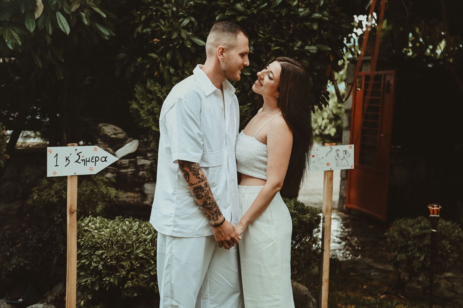 Black and white wedding photo of bride and groom gazing at each other outdoors among trees.