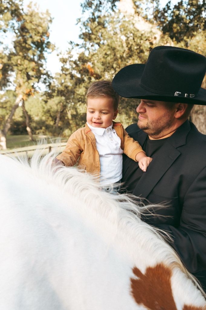 Young child reaching to pet a horse during a candid family photography session at Windmill Stables.