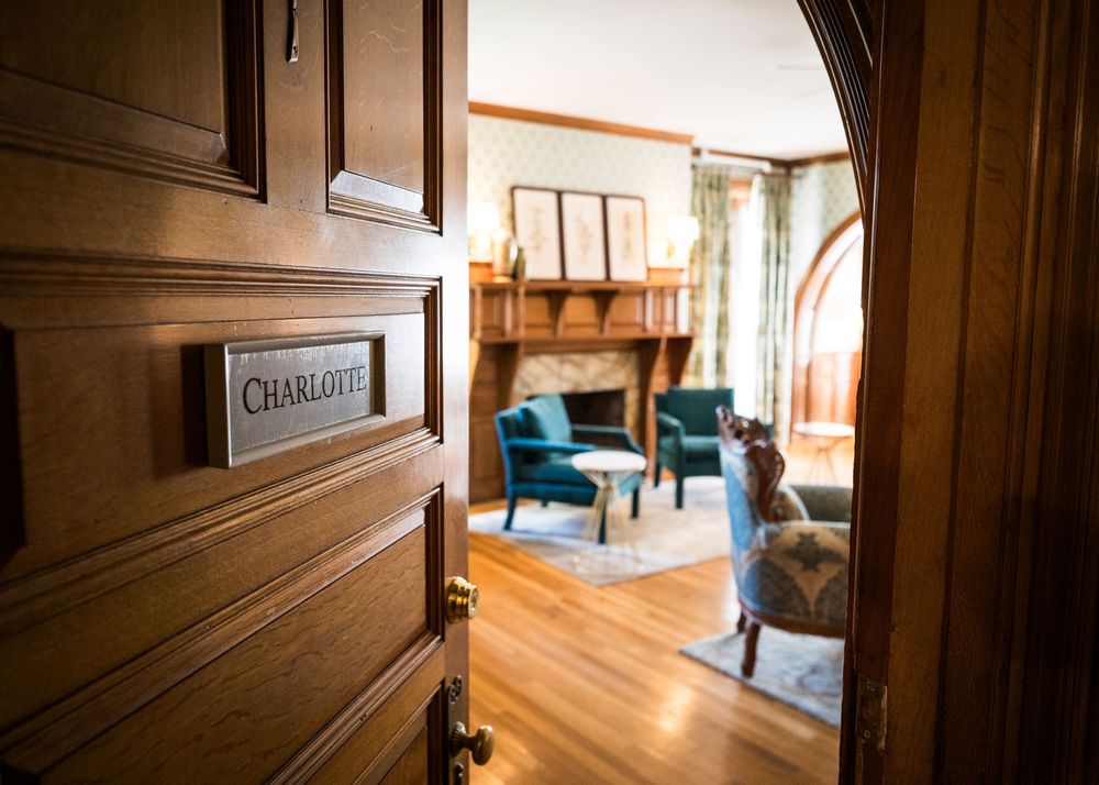Elegant Charlotte room with teal chairs, wood paneling, fireplace, and hardwood floors in a charming inn.