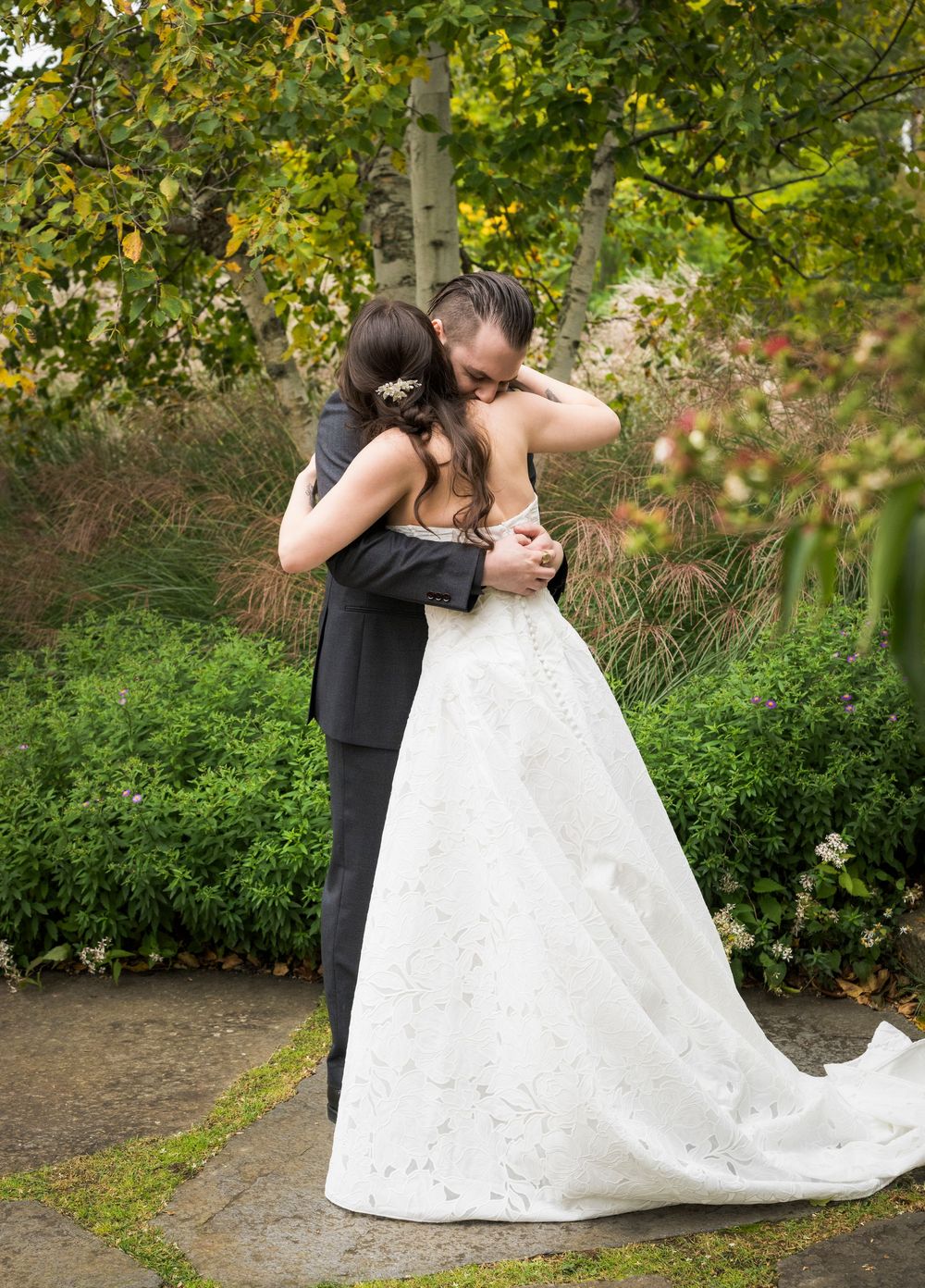 Bride and groom share an emotional first look embrace in a lush garden setting on their wedding day.