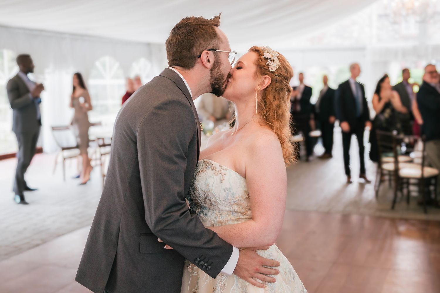 Bride and groom sharing a kiss mid-dance, her hand resting on his chest.
