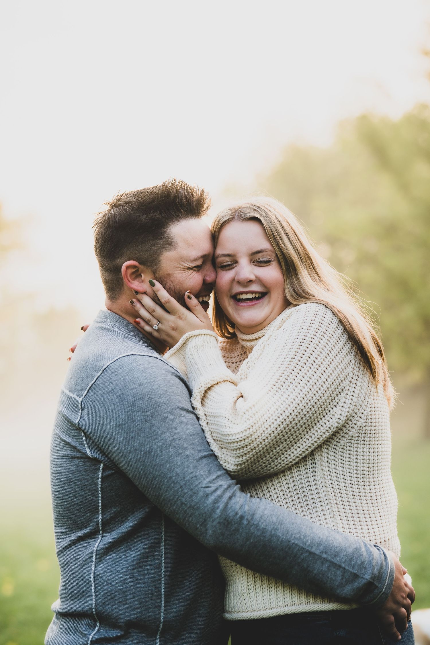 Couple sharing intimate moment outdoors wearing cozy sweaters in natural setting.