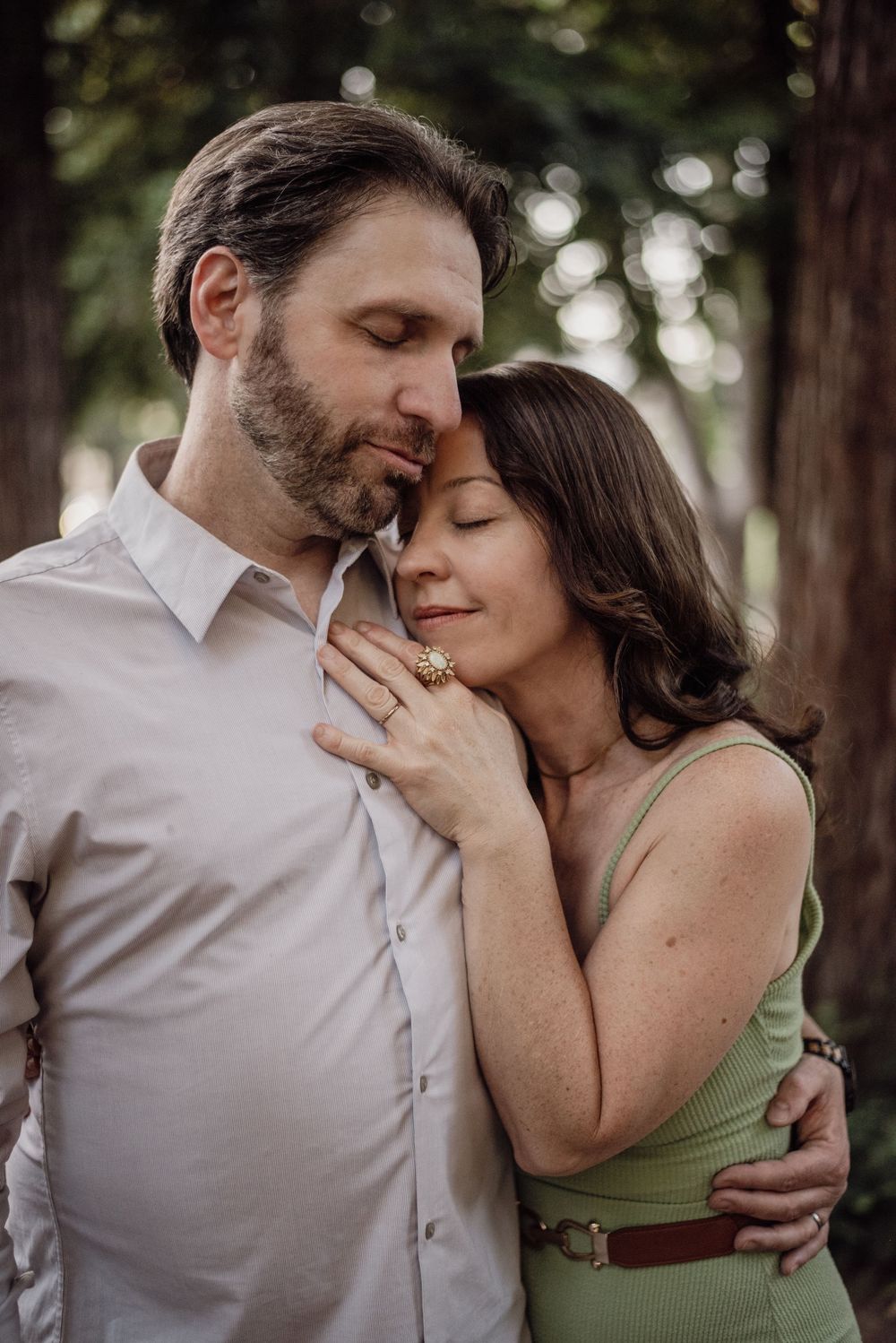 A couple lost in their own little world beneath the trees, surrounded by nature, quiet moments, and the ease of being together.