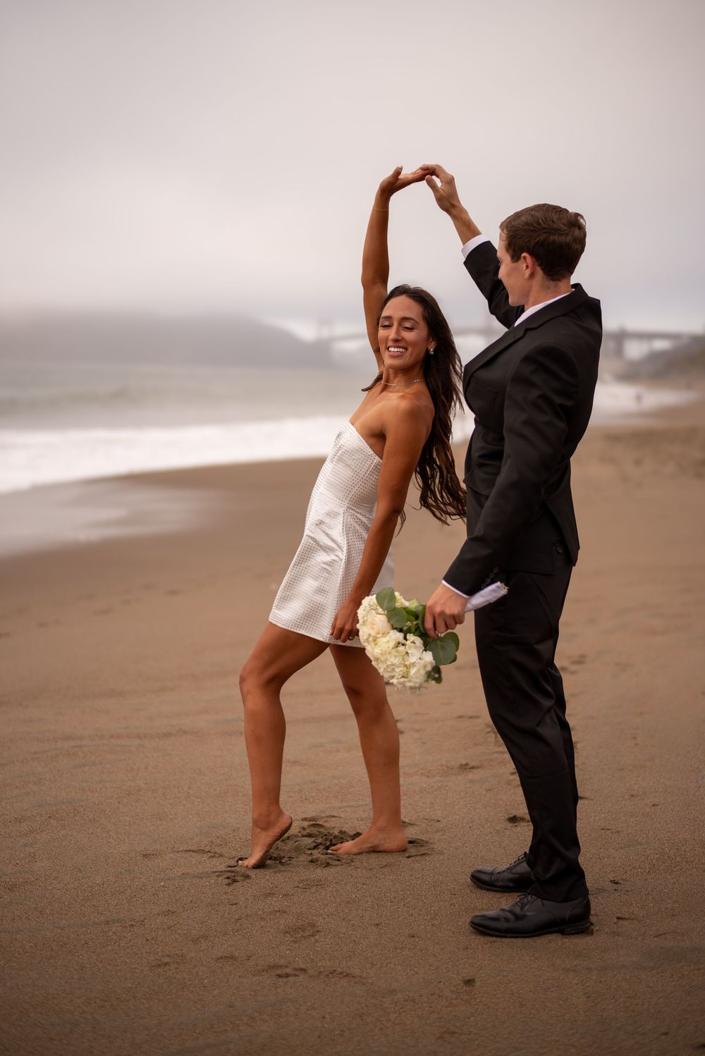 A quiet, windswept moment between two people completely wrapped up in each other, with the Golden Gate fading into the background.