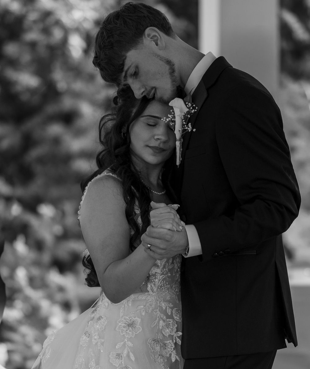 Black and white romantic portrait of newlyweds sharing a tender embrace during their first dance.