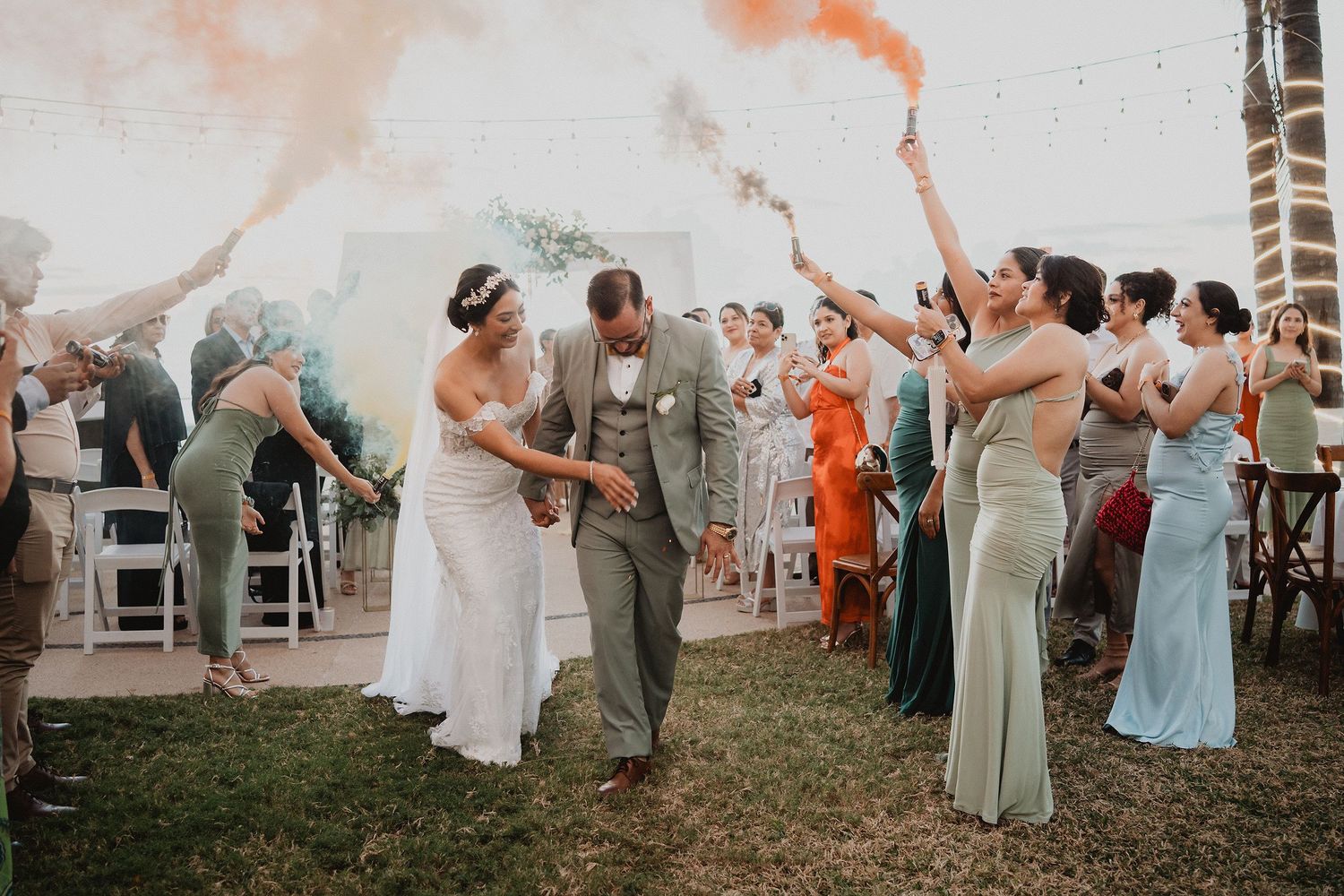 Novios saliendo de su ceremonia entre humo de colores en Park Royal Mazatlán.