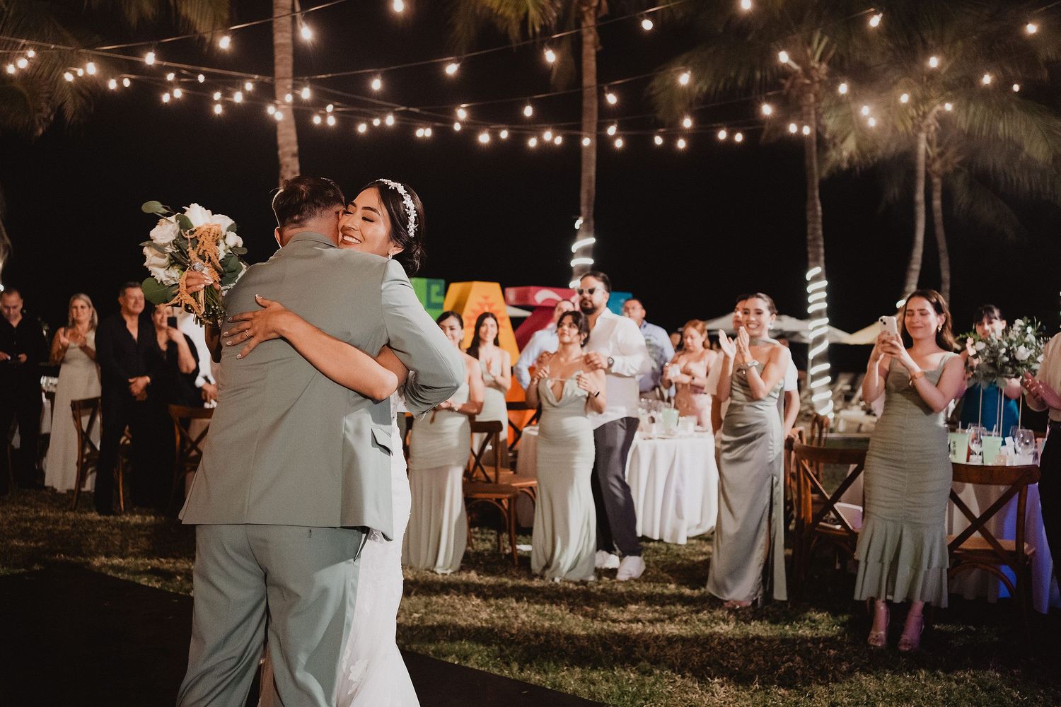 Novios abrazándose durante la recepción rodeados de sus invitados.