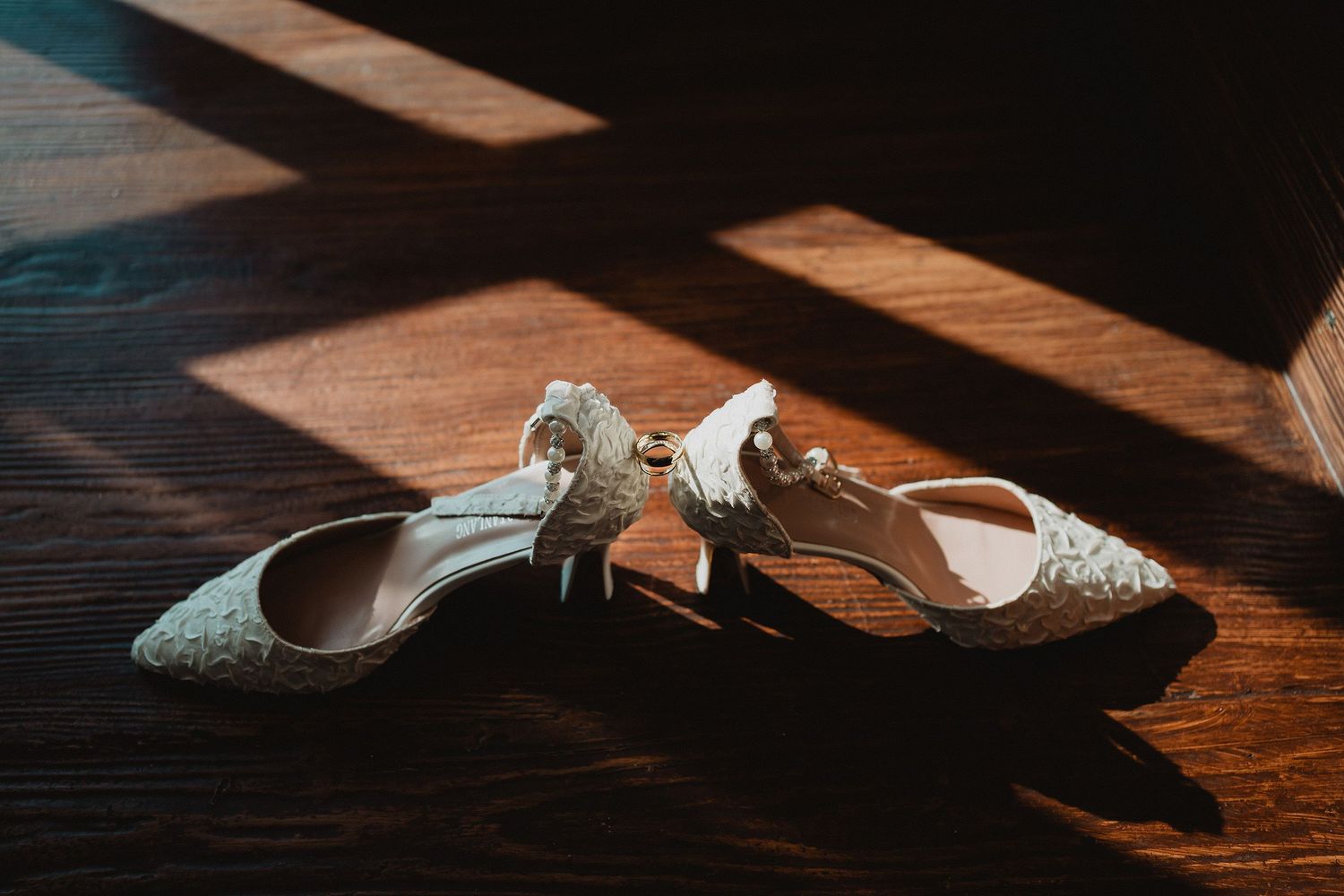 Zapatos de novia y anillos iluminados por la luz de la habitación.