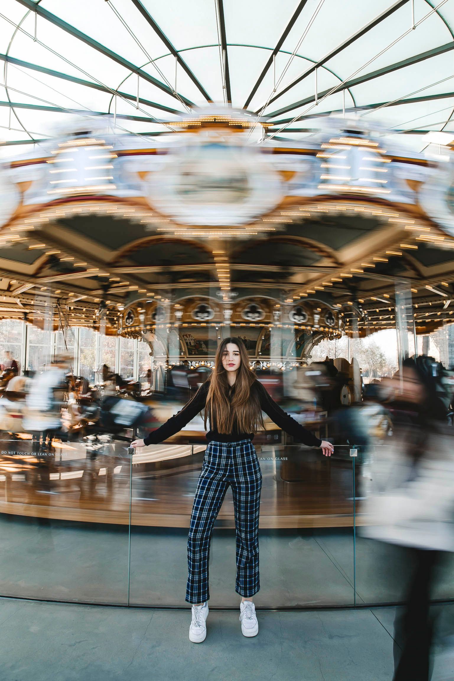 Person posing in front of spinning carousel with motion blur effect.