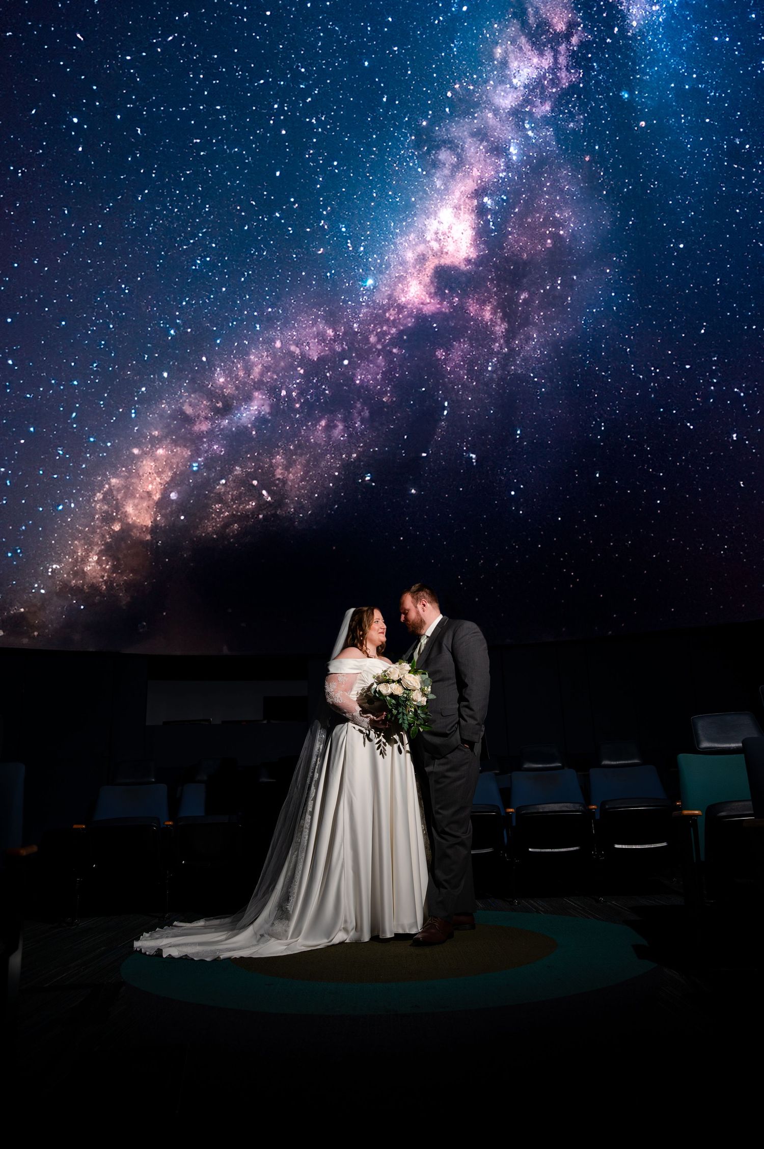 Bride and groom share a romantic moment under a stunning Milky Way galaxy sky at a celestial-themed wedding.