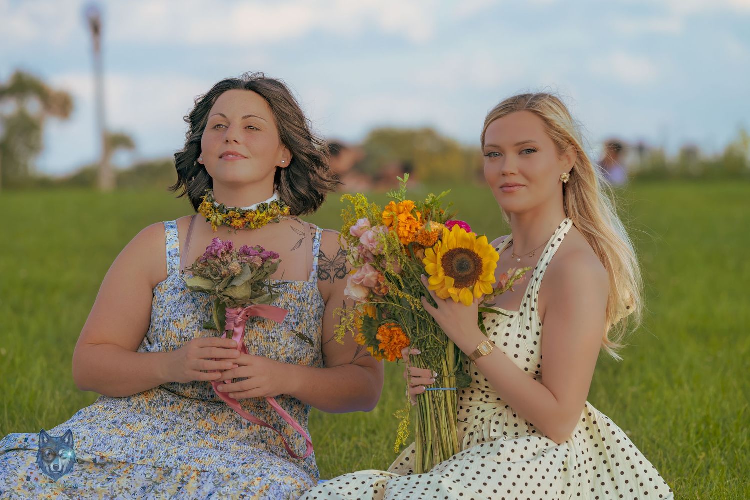 Two women sitting in field holding colorful flower bouquets including sunflowers. Chi.Shooters meet gabbsbosh