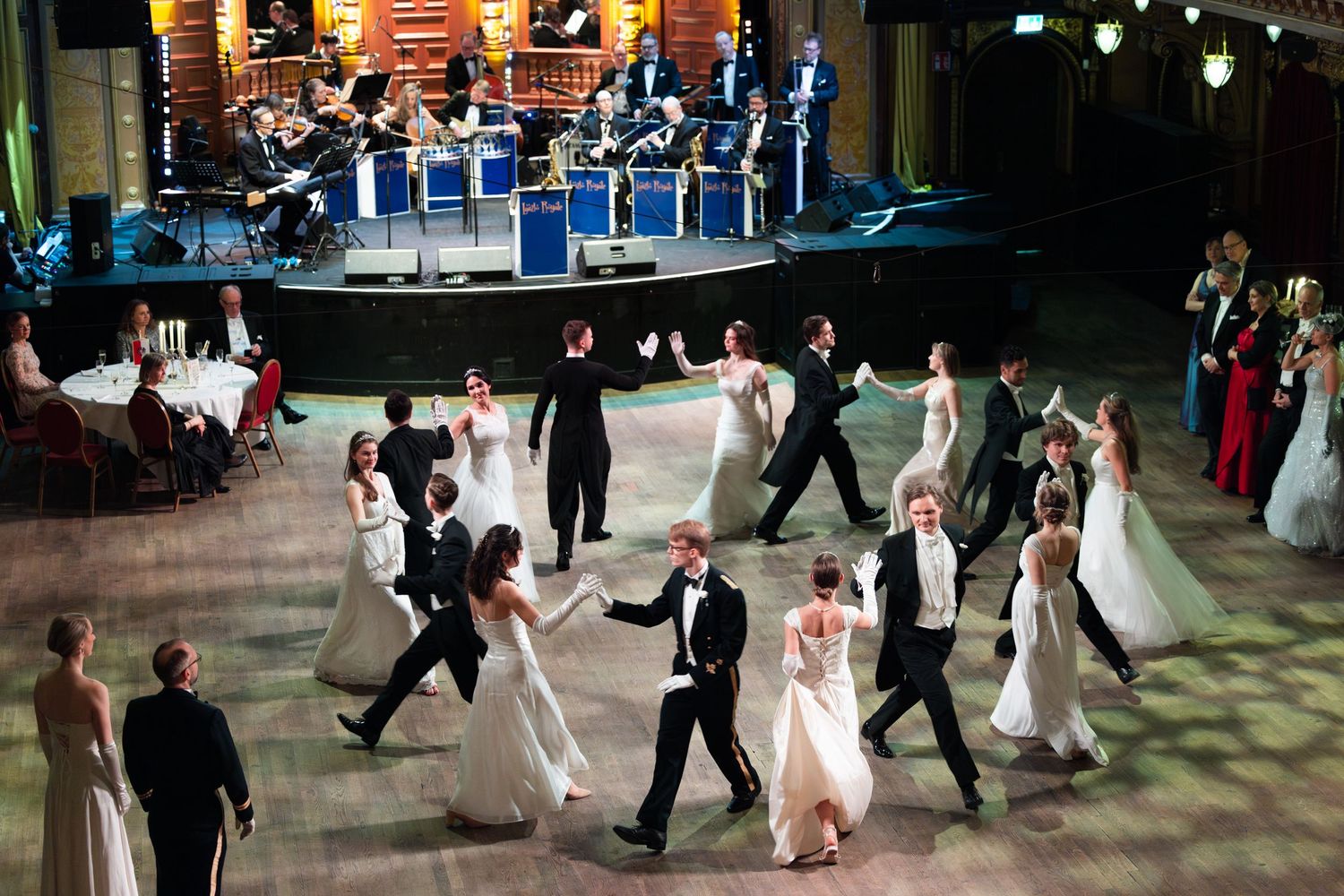 Ballroom dancers in formal attire performing waltz on stage at elegant gala event.