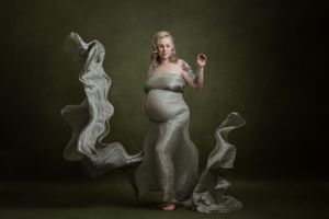 Expectant mother in a silver gown with an artistic double-exposure figure beside her.