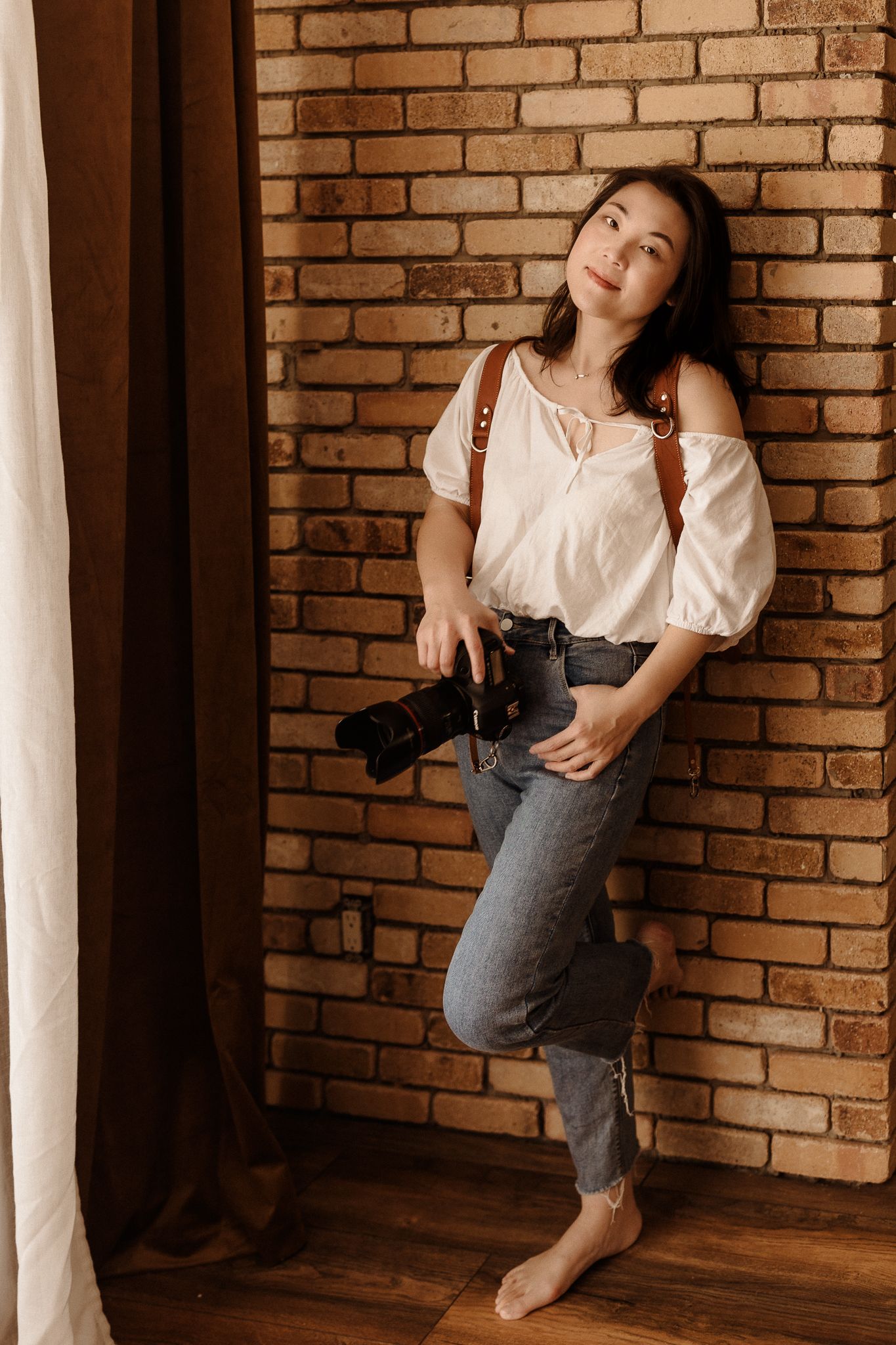 Artistic portrait session against a brick wall backdrop in vintage style lighting.