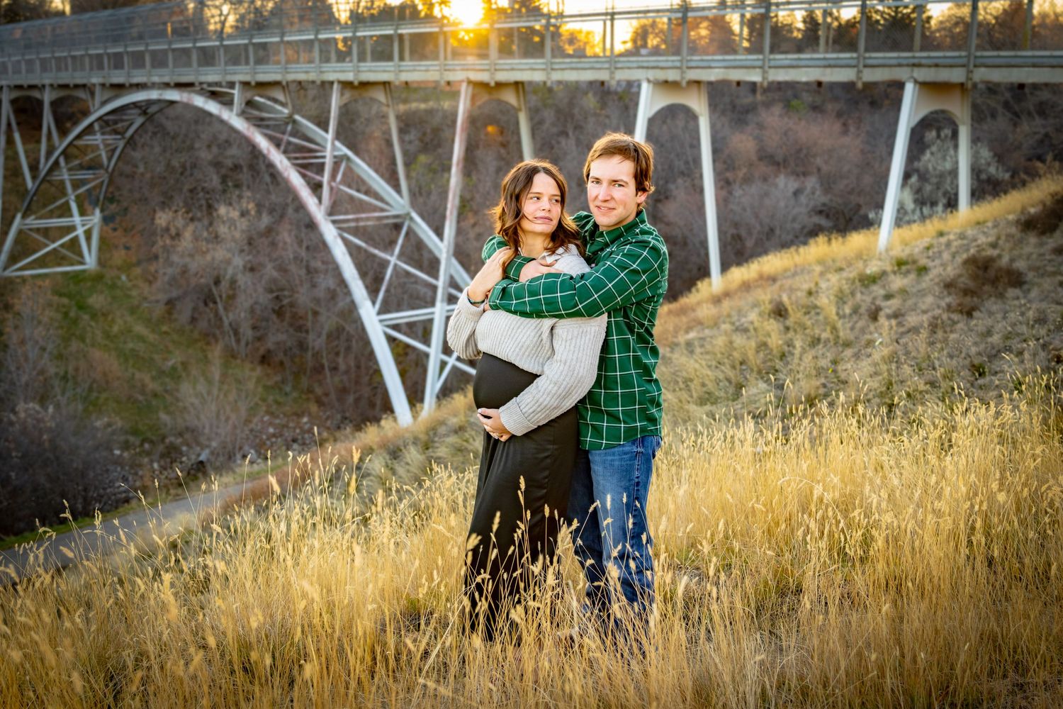 a couple in front of a bridge.