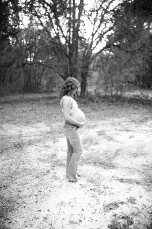 Black and white photo of a person in profile showing pregnant belly in outdoor setting.