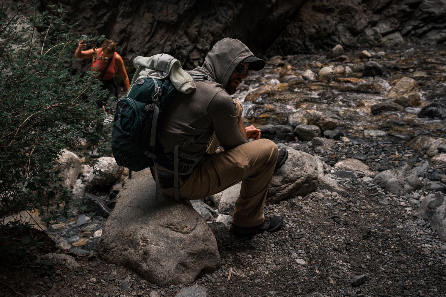 Photographer with backpack crouching on rocky terrain to capture a shot. zapata falls colorado sand dunes  hiking