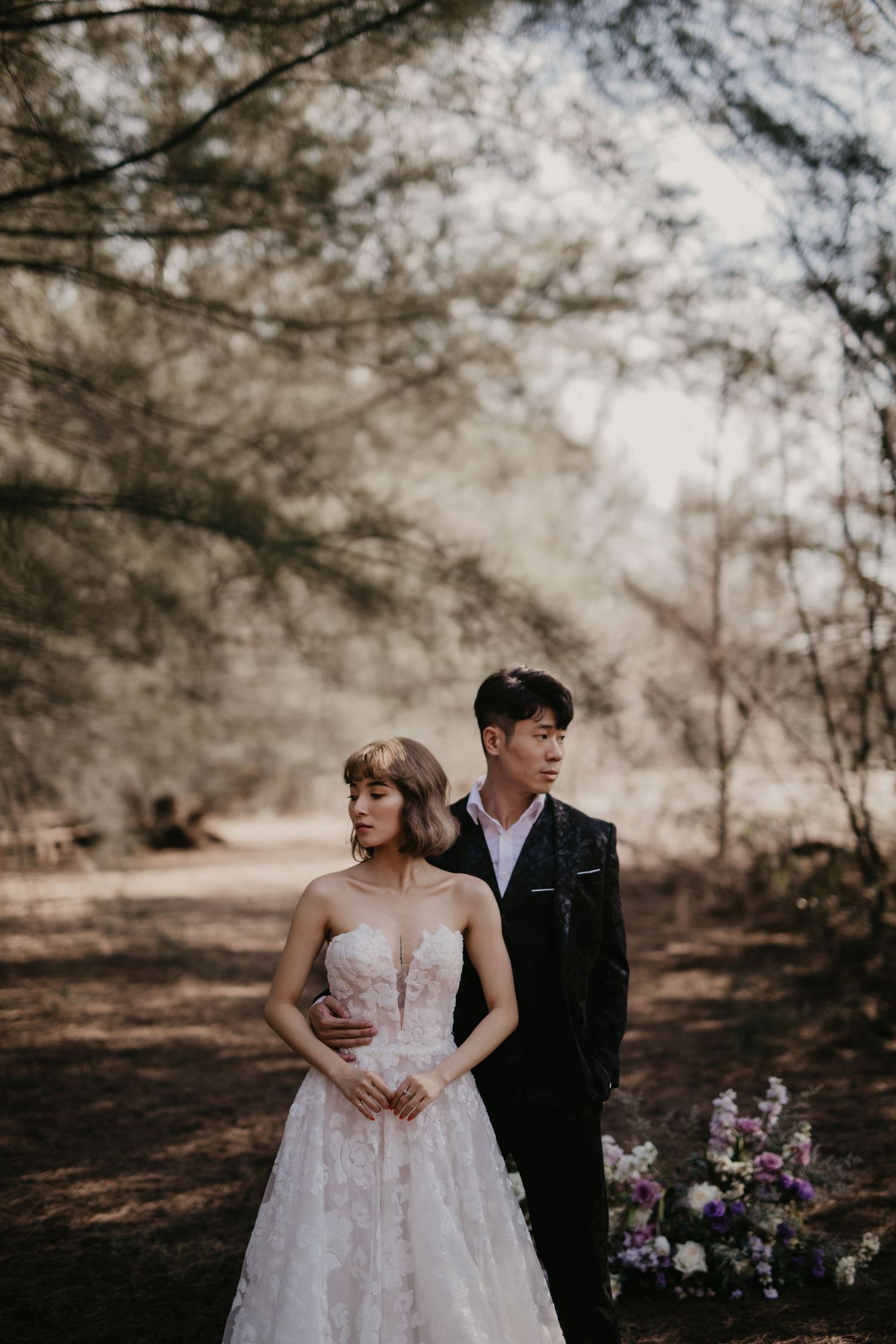 Artistic wedding photography in a forest setting with soft lighting and romantic poses.