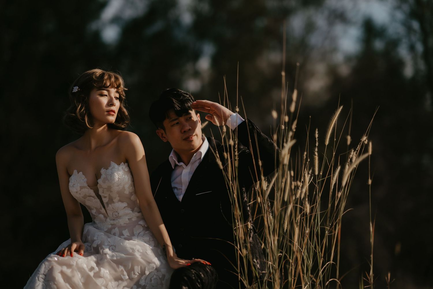 A couple shares an intimate moment among tall grass at golden hour.