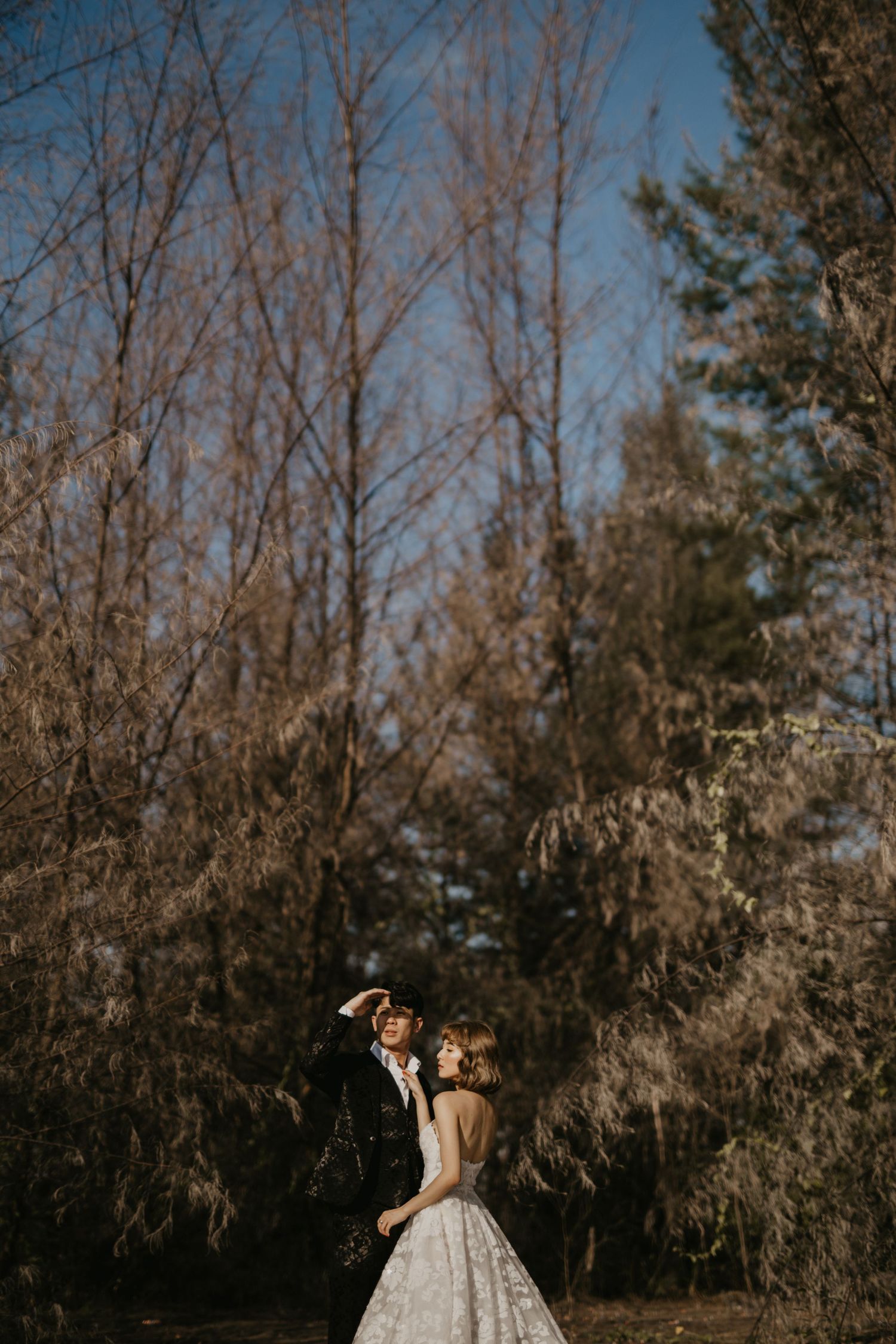 A romantic wedding portrait captured in a natural setting with bare winter trees.