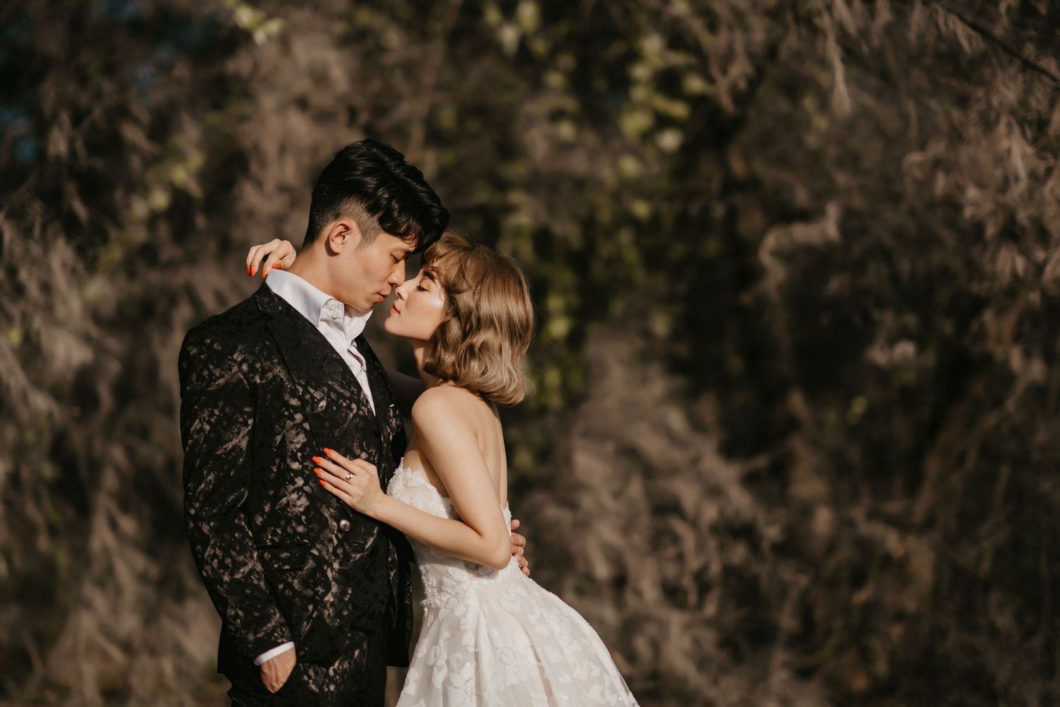A tender moment between newlyweds captured in moody forest lighting.