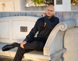 Professional portrait series of someone sitting on a concrete bench in an outdoor urban setting with natural lighting.