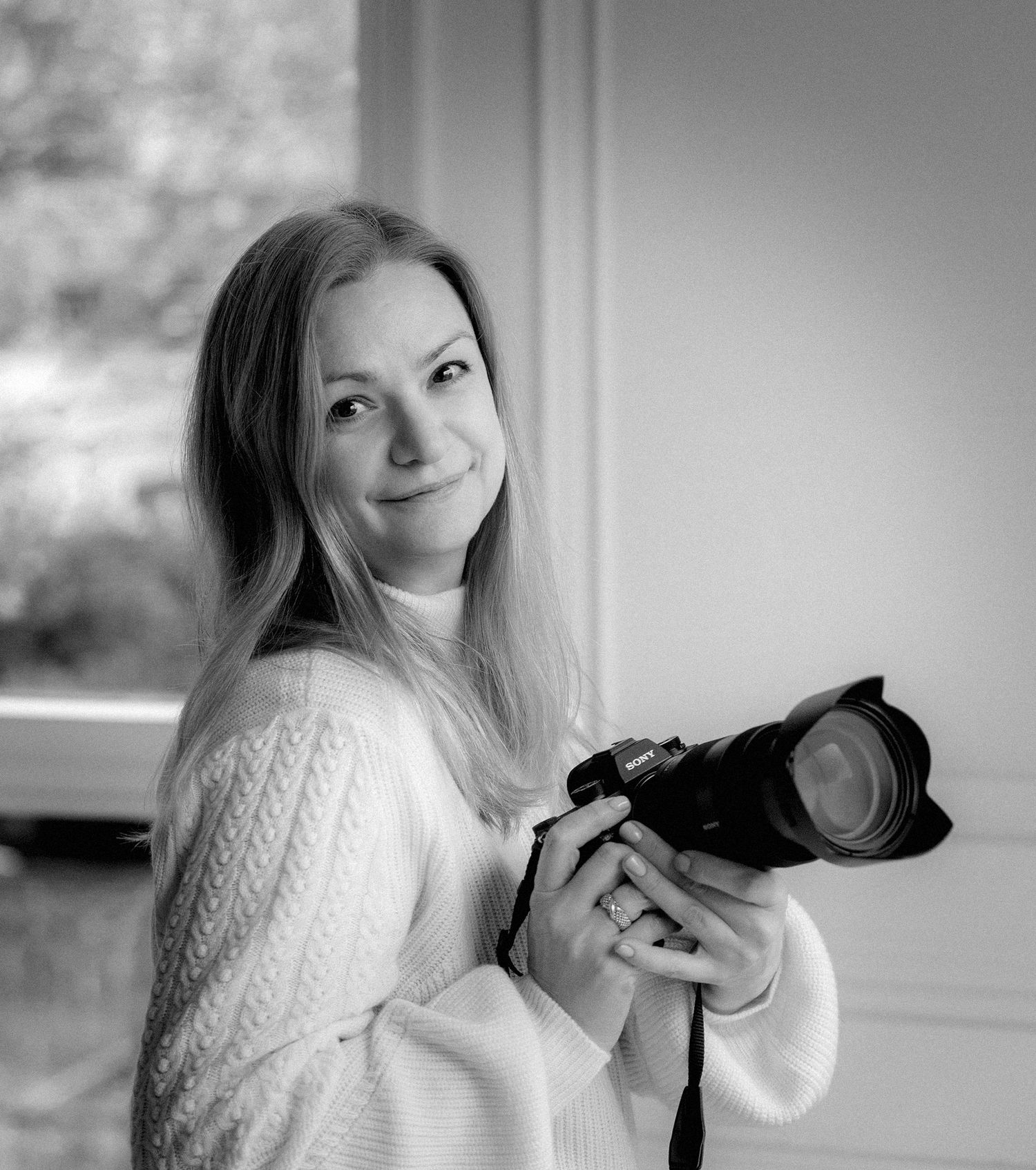 Black and white portrait of a photographer holding a professional camera.