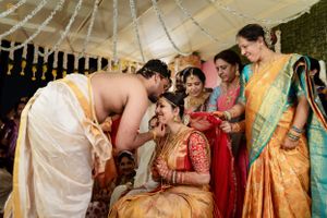 Traditional Indian wedding ceremony with guests in colorful attire under a decorated canopy.
