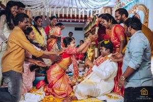 Wedding guests shower blessings and flowers during a traditional South Indian marriage ceremony.