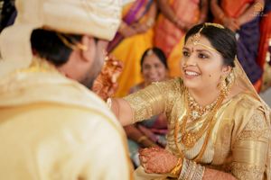 Traditional wedding ceremony with participants in formal attire exchanging ceremonial gestures.