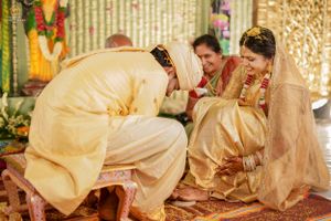 Traditional wedding ceremony with couple in cream colored outfits performing rituals.