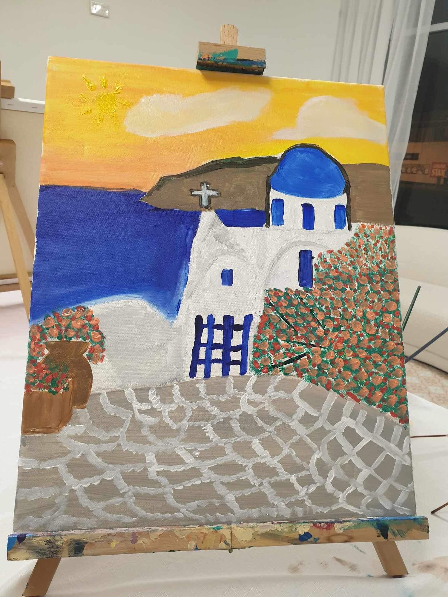 Painting of a white Greek church with blue dome against yellow sky and stone pathway.