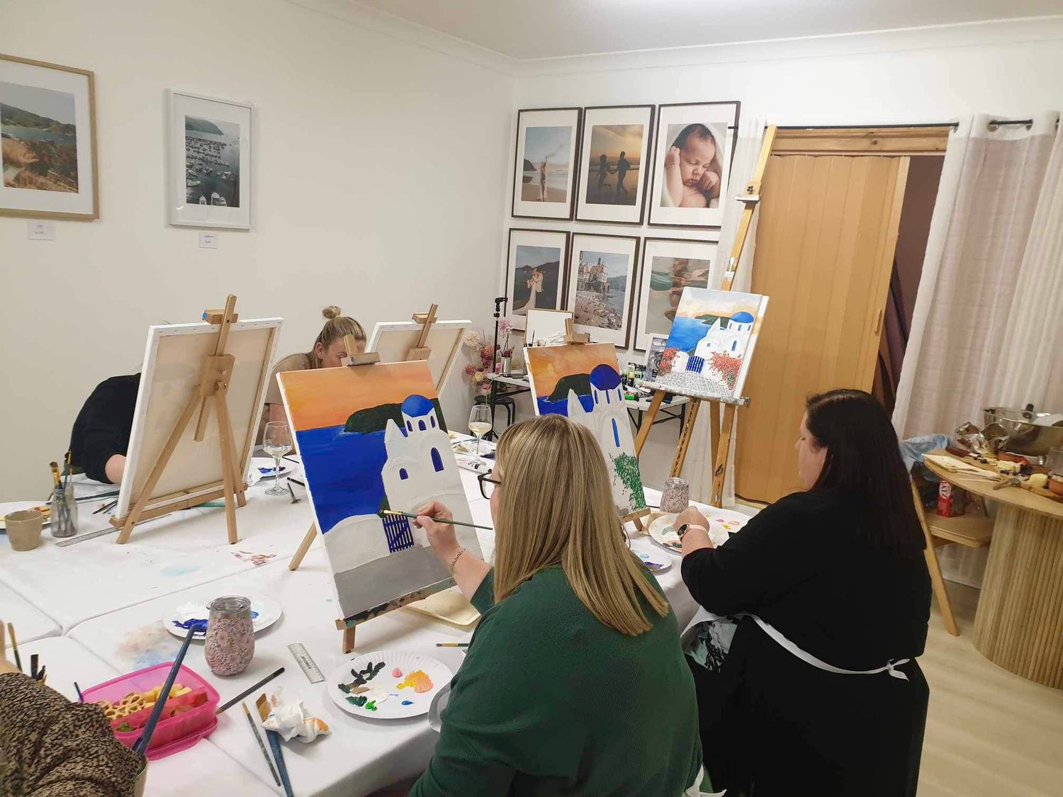 Students working on paintings at easels in an art studio classroom setting.