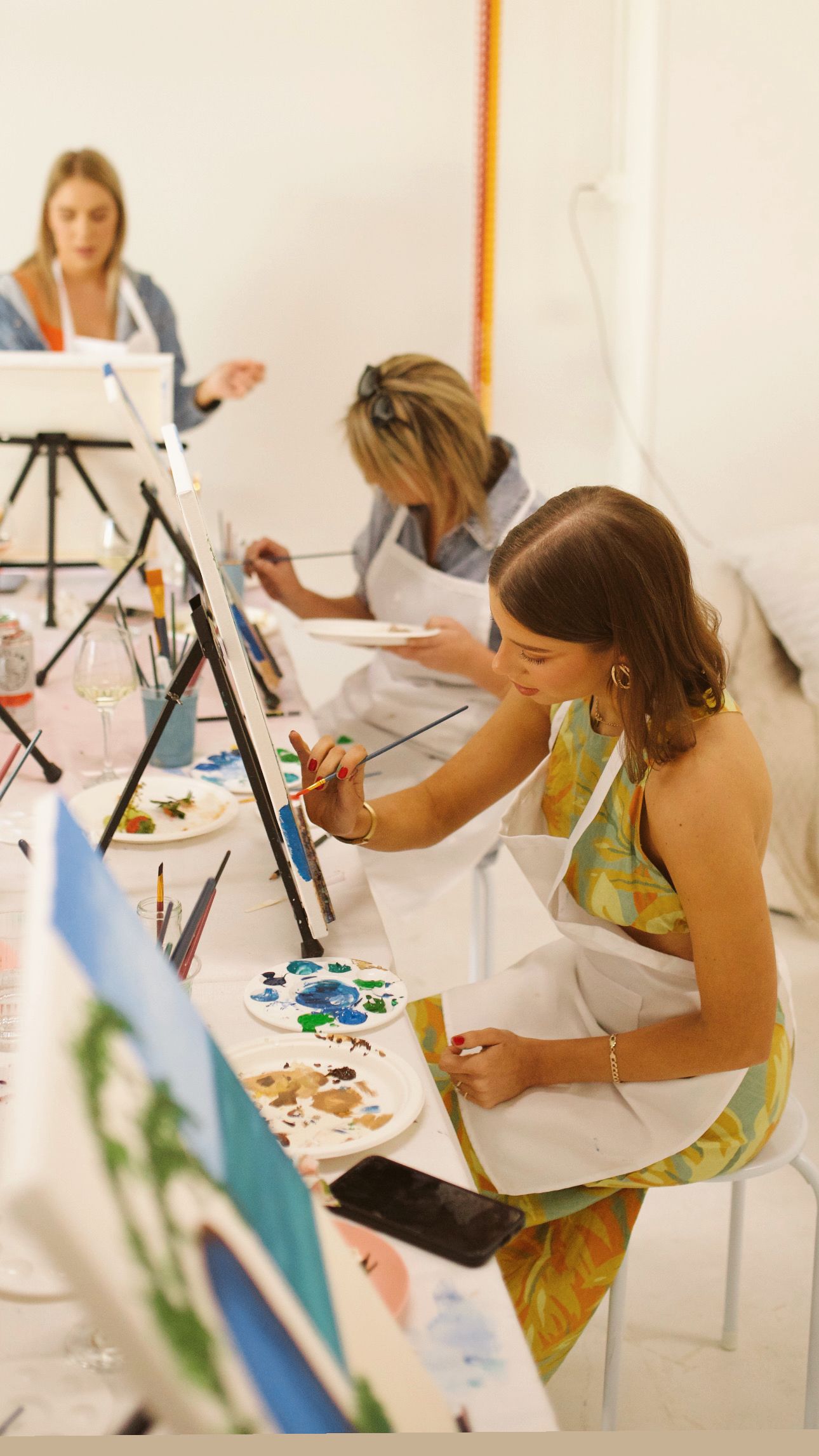 Art students working on paintings at easels during a creative workshop session.