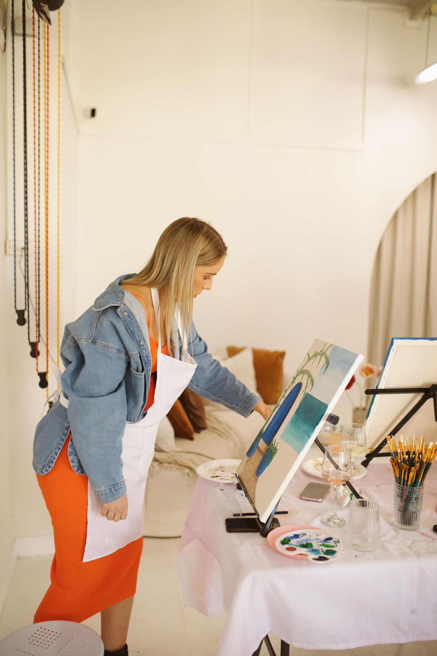 Artist working on a seaside painting at an easel during a studio art class.