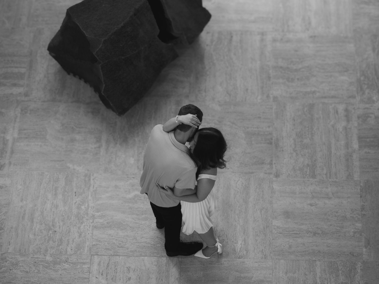 An overhead view of a dancing couple embracing on a patterned floor.