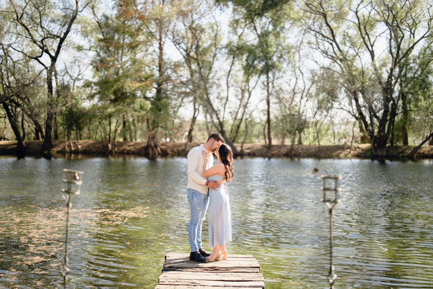 Romantic couple embracing on wooden dock by tranquil lake.