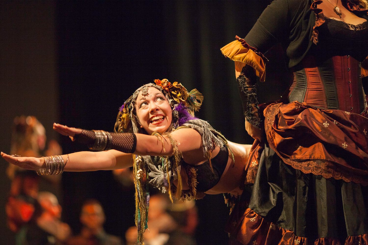 Performer in elaborate costume stretches out their arms during a theatrical performance.