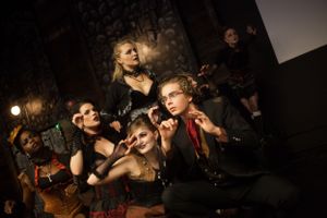 Dramatic low-light theatrical performance with performers in dark costumes.