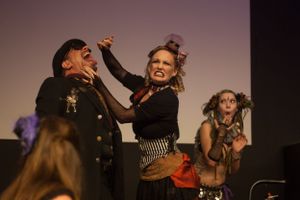 Dramatic stage performance with performers in vintage costumes engaging in theatrical confrontation.