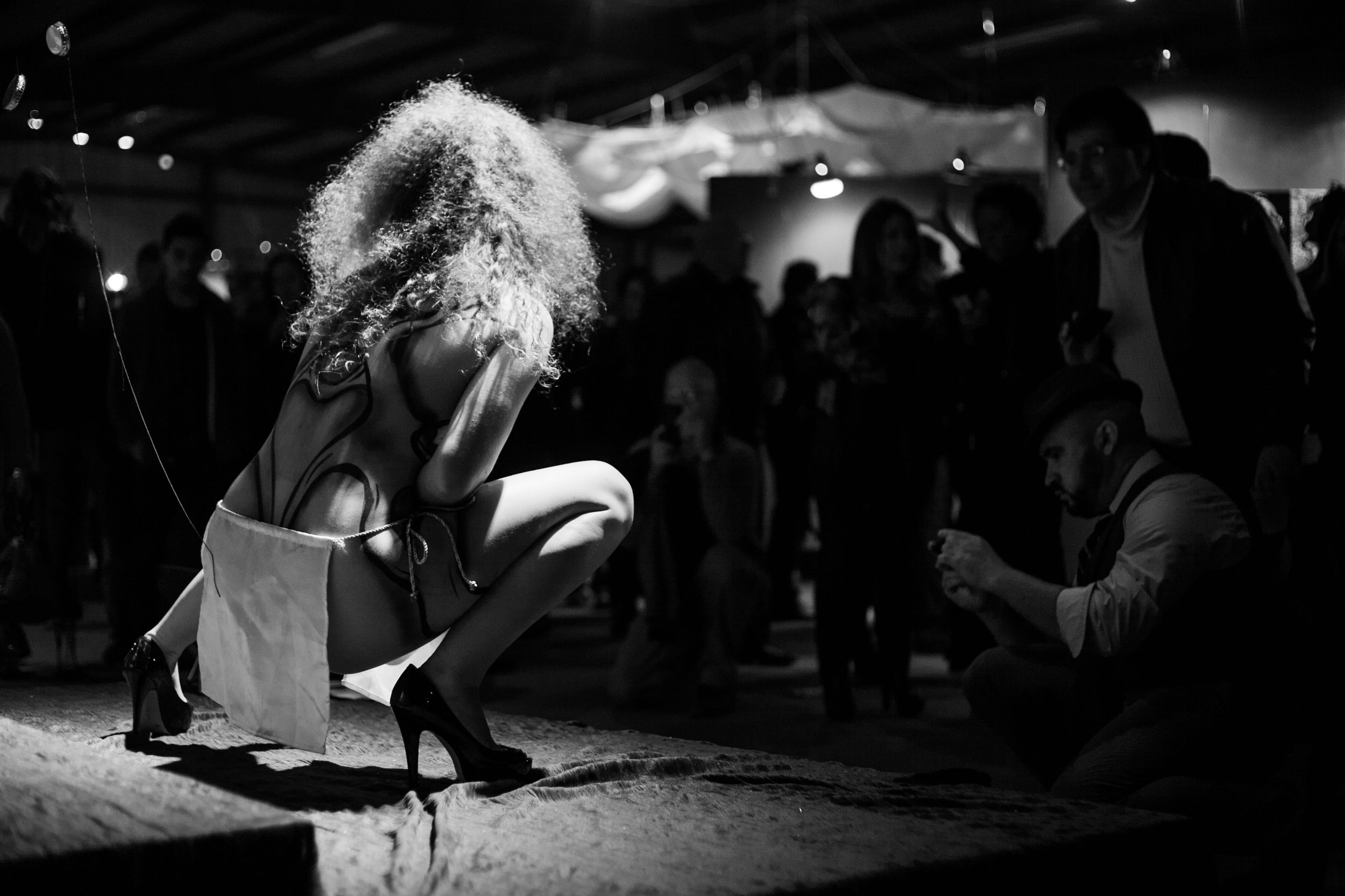Black and white photo of performer in dynamic movement on stage.