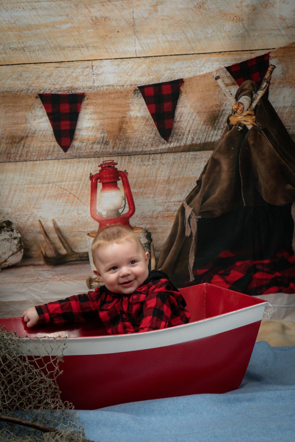 Red and black buffalo plaid themed nursery setup with lantern and pennant banner against rustic wooden wall.