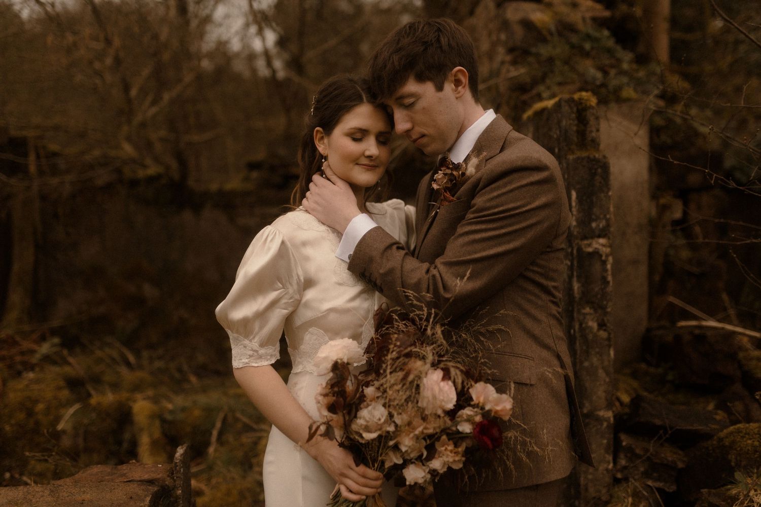 Romantic autumn wedding portrait with warm sepia tones and vintage-style formal attire.