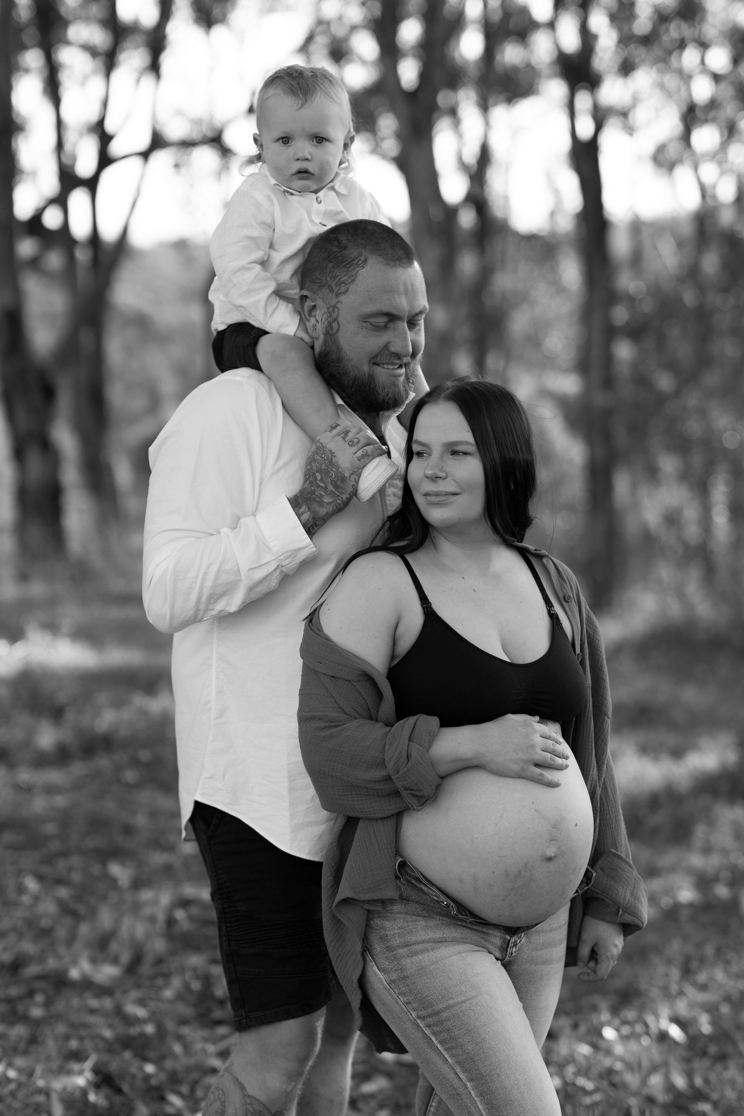 Family maternity photo in black and white with toddler sitting on shoulders.