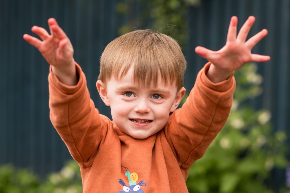Little boy with his hands in the air during a nursery photoshoot, in Ashtead, Surrey