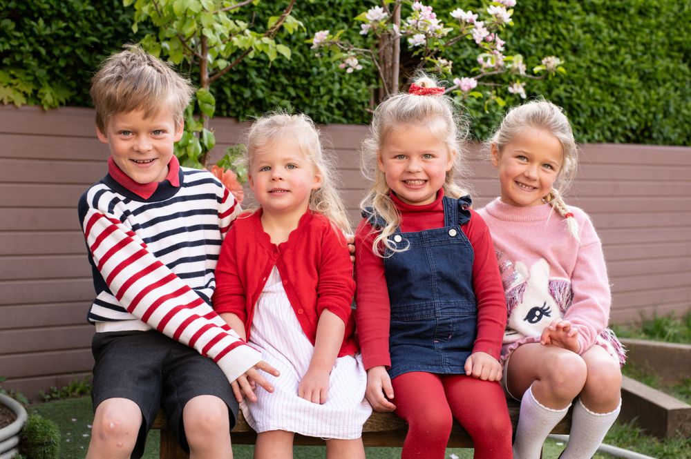 4 siblings sitting on a bench during a nursery photoshoot, in Ashtead, Surrey