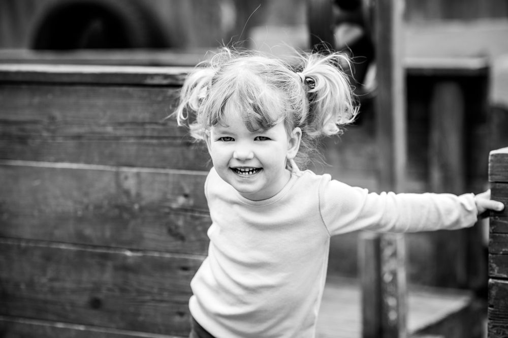 Young girl smiling cheekily during a nursery photoshoot, in Ashtead, Surrey