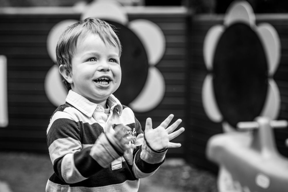 Boy with a cheeky grin looking at bubbles during a nursery photoshoot., in Ashtead, Surrey